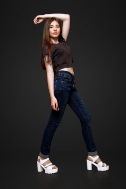 Siyah arka plan üzerinde stüdyoda kot pantolon ve t-shirt giymiş güzel bir 13 yaşında kız