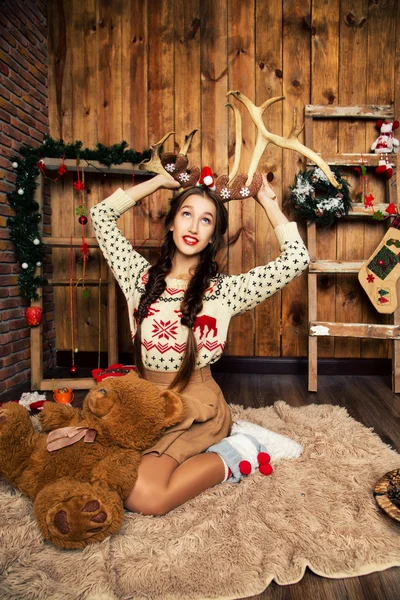 Młoda emocjonalna dziewczyna z warkoczami ubrana w noworoczne ubrania. Studio z dekoracjami świątecznymi. — Zdjęcie stockowe
