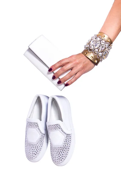 Frauenhand mit weißer Leder-Clutch und weißen Schuhen mit Strass auf weißem Hintergrund isoliert — Stockfoto