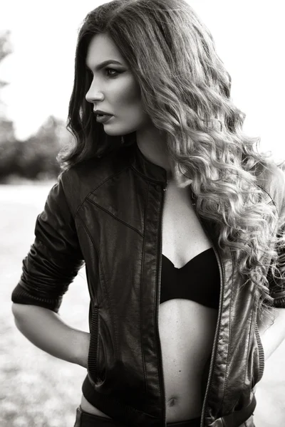 Fashion model with long curly hair wearing leather jacket posing — Stock Photo, Image