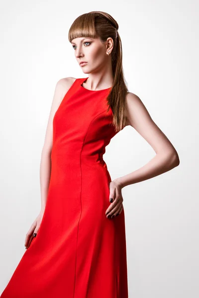 Όμορφη γυναίκα μοντέλο που θέτουν σε απλή κομψό κόκκινο φόρεμα στο στούντιο σε άσπρο φόντο — Φωτογραφία Αρχείου