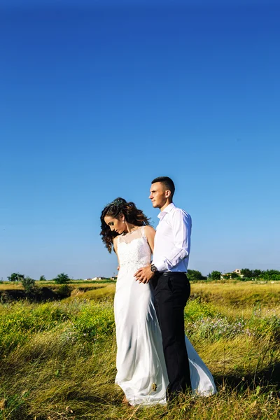 Belo casal no campo, Amantes ou recém-casados posando no pôr do sol com céu perfeito — Fotografia de Stock