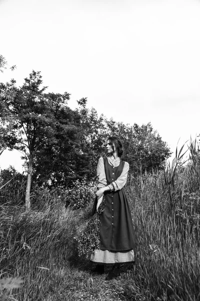 Retrato ao ar livre de uma bela mulher morena em vestido azul no campo. Foto em preto e branco — Fotografia de Stock
