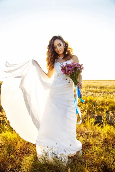 Young woman in wedding dress outdoors. beautiful bride in a field at sunset