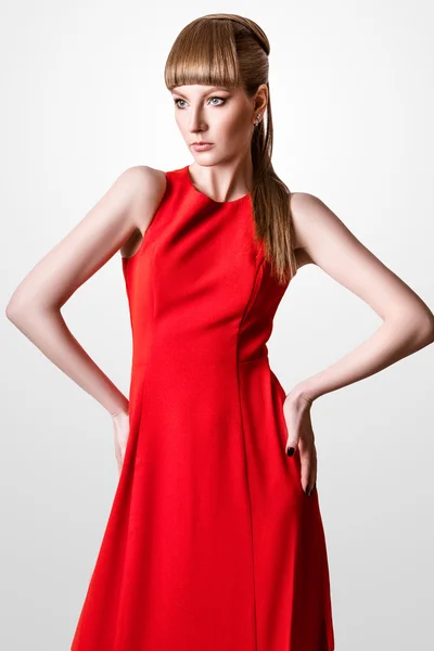 白い背景のスタジオでシンプルなエレガントな赤いドレスでポーズをとる美人モデル — ストック写真