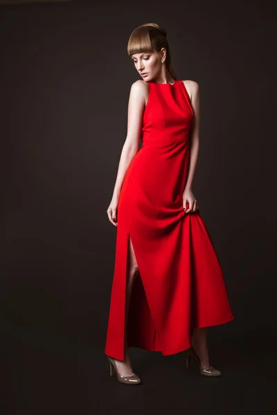 Beautiful woman model posing in simple elegant red dress in the studio on black background — Stock Photo, Image