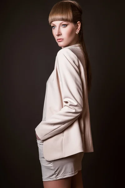 Vacker kvinna modell poserar i enkel elegant i en ljus kostym i studion på svart bakgrund — Stockfoto