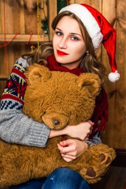 beautiful blonde girl in a santa hat sitting on a chair