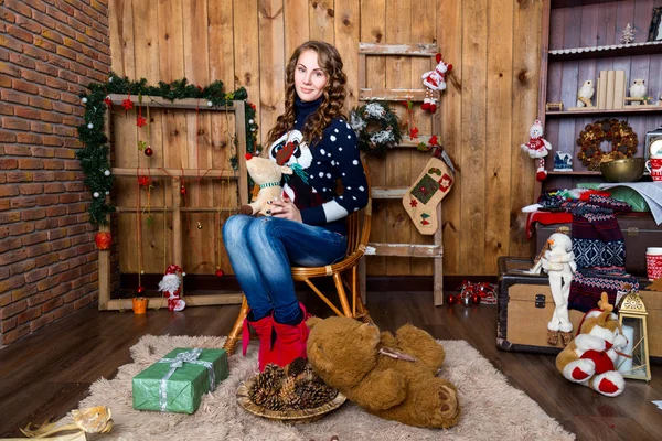 Dziewczyna z zabawką w ręku, siedząc w pokoju z drewnianą ścianę — Zdjęcie stockowe