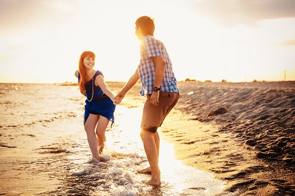 A young couple enjoys a mid summer late afternoon, on a wet san — Stockfoto