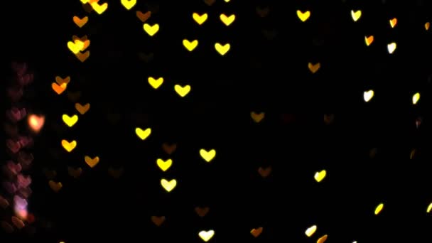 Bulanık sarı turuncu şekilli sıcak kalpler duvarda güzel bir gece ışığı şehirde. — Stok video