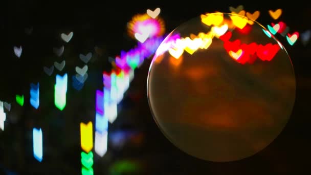 Kristálygömb az üvegpadlón és a szív alakú szivárvány fények az utcáról tükröződnek a labda felületén — Stock videók