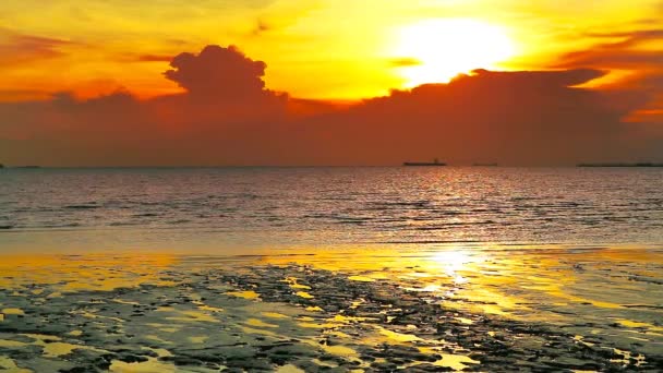 Puesta de sol detrás nube oscura sobre mar y silueta buque de carga de estacionamiento en el horizonte — Vídeos de Stock