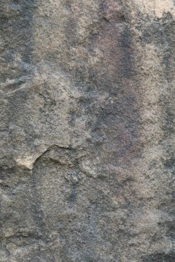 Close-up view of rough textured stone surface with natural patterns and colors, ideal for backgrounds, wallpapers, and design projects.