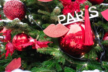 Parlak kırmızı süslemelerle süslenmiş bir çam ağacı, parlak dudaklar, kalın çiçekler, püsküller ve hassas yapay kar dokunuşlarıyla metalik 