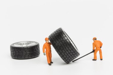 Atölye lastiği provası konsepti. Minyatür tamirciler oyuncak araba tekerleğini tamir ediyor. Kapatın..