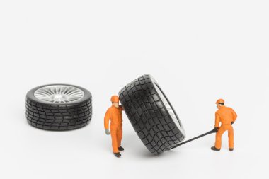 Atölye lastiği provası konsepti. Minyatür tamirciler oyuncak araba tekerleğini tamir ediyor. Kapatın..