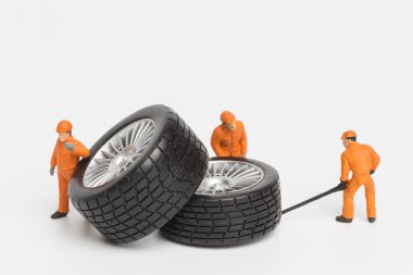 Atölye lastiği provası konsepti. Minyatür tamirciler oyuncak araba tekerleğini tamir ediyor. Kapatın..