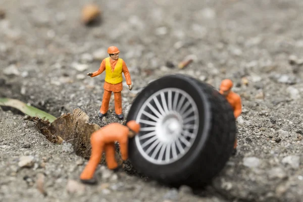 O conceito da montagem pneu oficina. Mecânica miniatura reparando roda de carro de brinquedo, close-up . — Fotografia de Stock