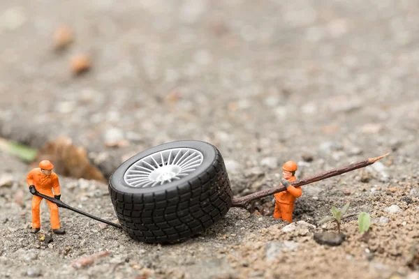 O conceito da montagem pneu oficina. Mecânica miniatura reparando roda de carro de brinquedo, close-up . — Fotografia de Stock