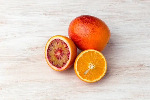 Skład sycylijskiej i normalne pomarańcze. Całości, pokroić na pół i segmentów. Na białym tle na chwilę drewna tło. — Zdjęcie stockowe