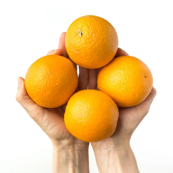 El concepto de una mano sosteniendo cuatro jugosas y maduras naranjas. Aislado sobre un fondo negro . — Foto de Stock