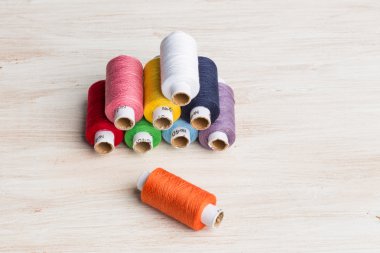 Bobin konu çok renkli. Ahşap arka plan üzerinde eski dikiş araçları.