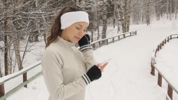 Jovem mulher ouvindo música e jogging fora no inverno — Vídeo de Stock