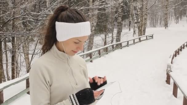 Fiatal nő, zenét hallgatni, és a téli jogging kívül — Stock videók