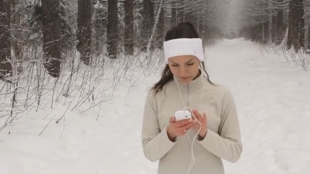 Jonge vrouw luisteren naar muziek en joggen buiten in de winter — Stockvideo