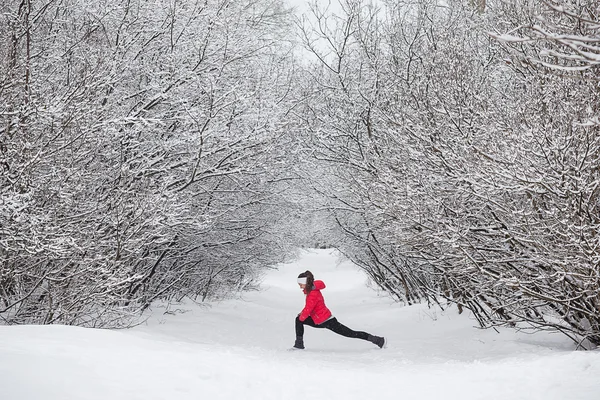 Молодая женщина делает упражнения на растяжку зимой — стоковое фото