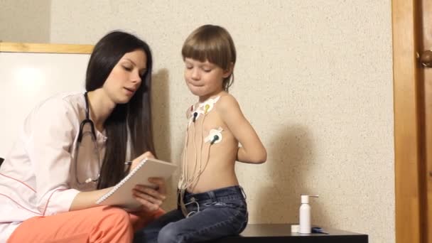 La cardióloga mujer realiza la recepción y examina al niño — Vídeo de stock