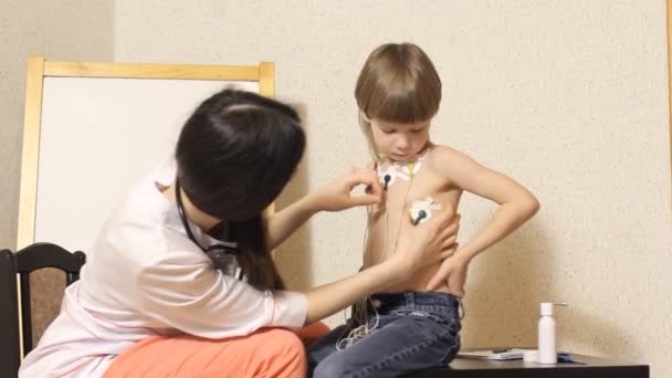 La cardióloga mujer realiza la recepción y examina al niño — Vídeo de stock