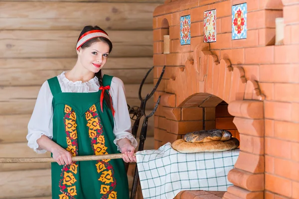 Женщина печет хлеб в русской печи — стоковое фото