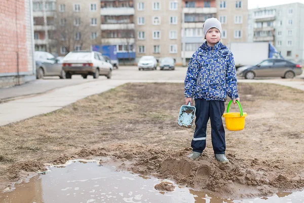 Мальчик играет в грязной луже — стоковое фото