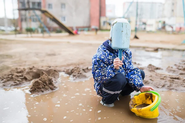 Мальчик играет в грязной луже — стоковое фото