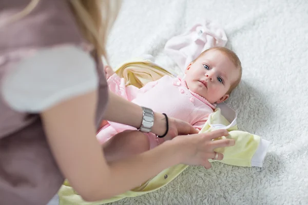 Anne giyim bebeğin üzerine koyar.