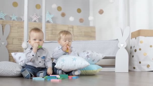 Dos gemelos bebé encantador están construyendo casas de cubos de colores — Vídeos de Stock