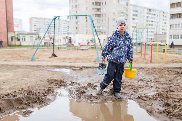 Boy playing in a muddy puddle