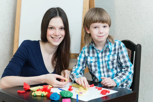 子供子供男の子と母親はカラフルな粘土を再生します。 ストックフォト