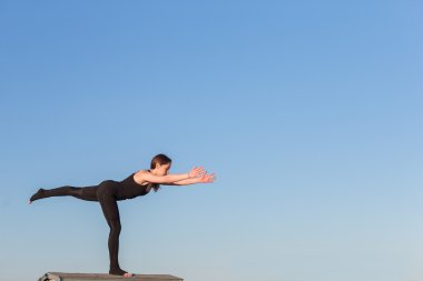 Genç kadın çatıda yoga yaparken