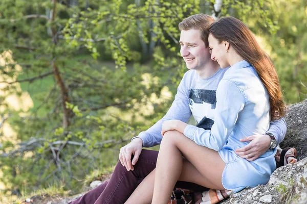 Young couple sitting on the edge of a cliff — Stock Photo, Image