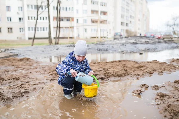 Мальчик играет в грязной луже — стоковое фото