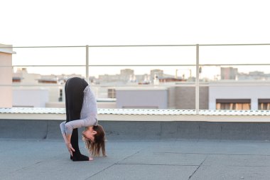 Genç kadın çatıda yoga yaparken