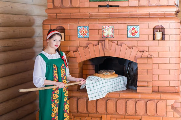 Frau backt Brot in russischem Ofen — Stockfoto