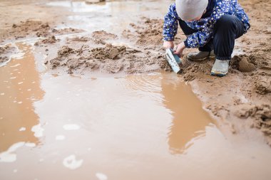 Boy playing in a muddy puddle clipart