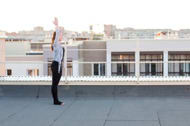 Genç kadın çatıda yoga yaparken