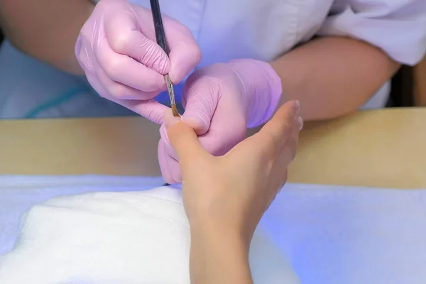 Mestre manicure é pintar unhas gel goma laca usando escova na clínica de beleza. — Fotografia de Stock