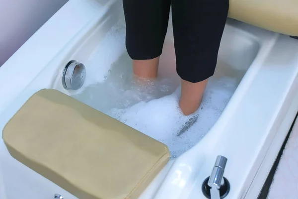 Pernas de cliente mulher no banho com espuma na cadeira de pedicure, pernas vista closeup. — Fotografia de Stock