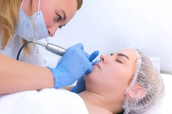 Cosmetoloog het maken van permanente make-up op vrouwen lippen met behulp van tattoo machine. — Stockfoto